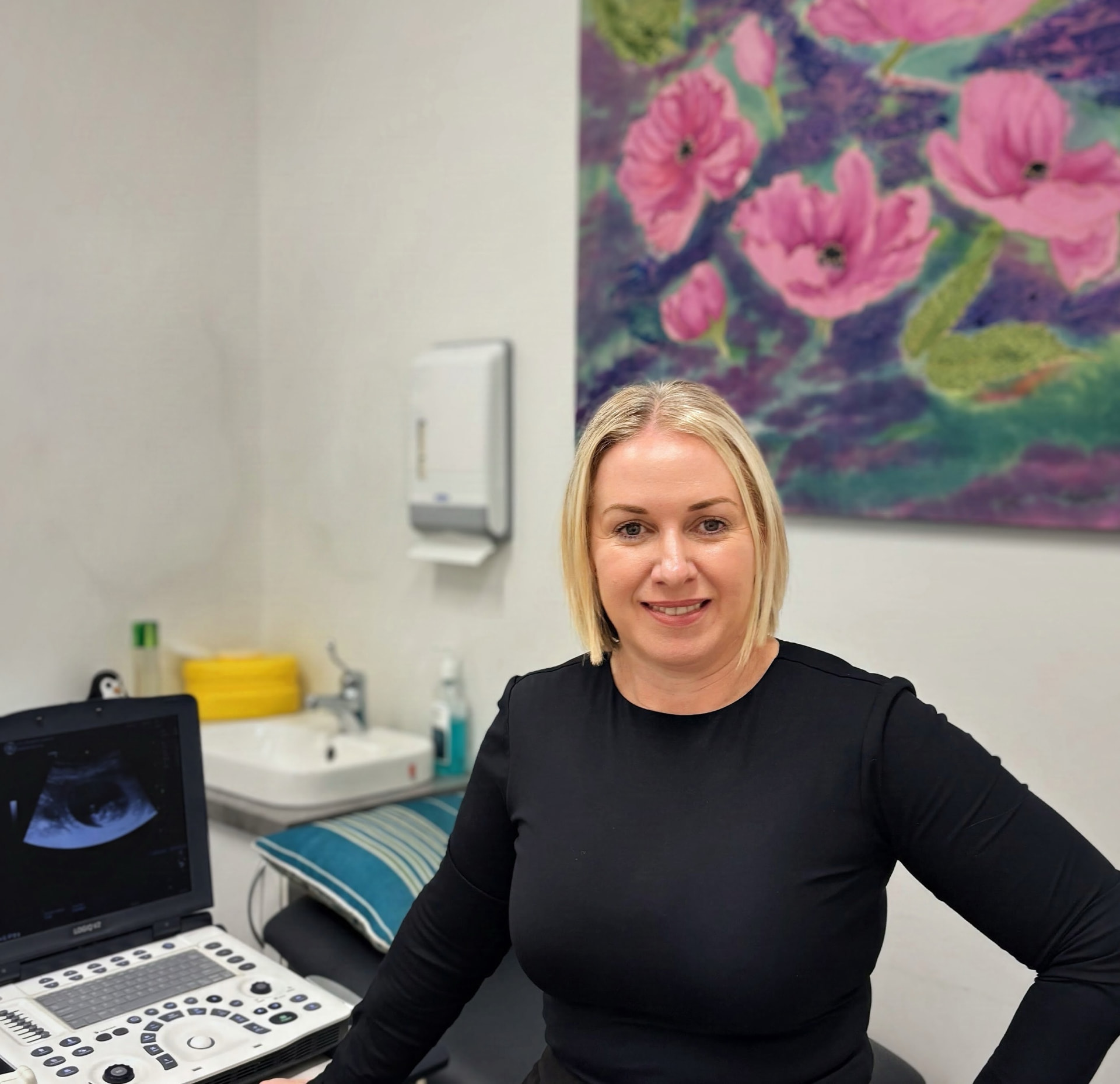 Narelle Ashworth, Endorsed Midwife, smiling in her Cairns clinic room beside the ultrasound machine - The Midwife's Nest, Cairns