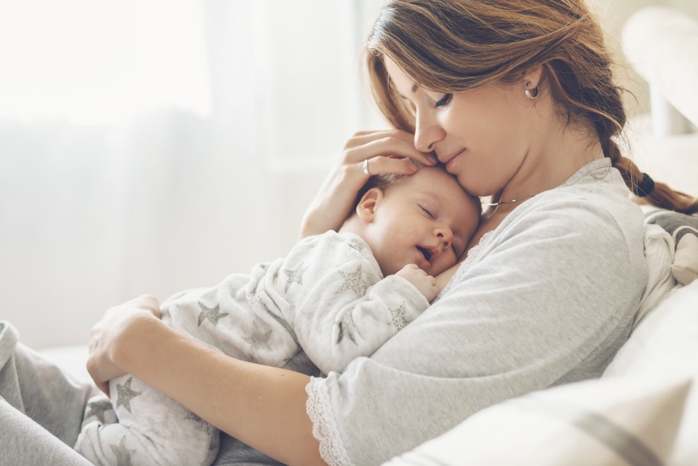 Mother cradling her sleeping newborn close in a bright, calm room after birth - The Midwife's Nest, Cairns