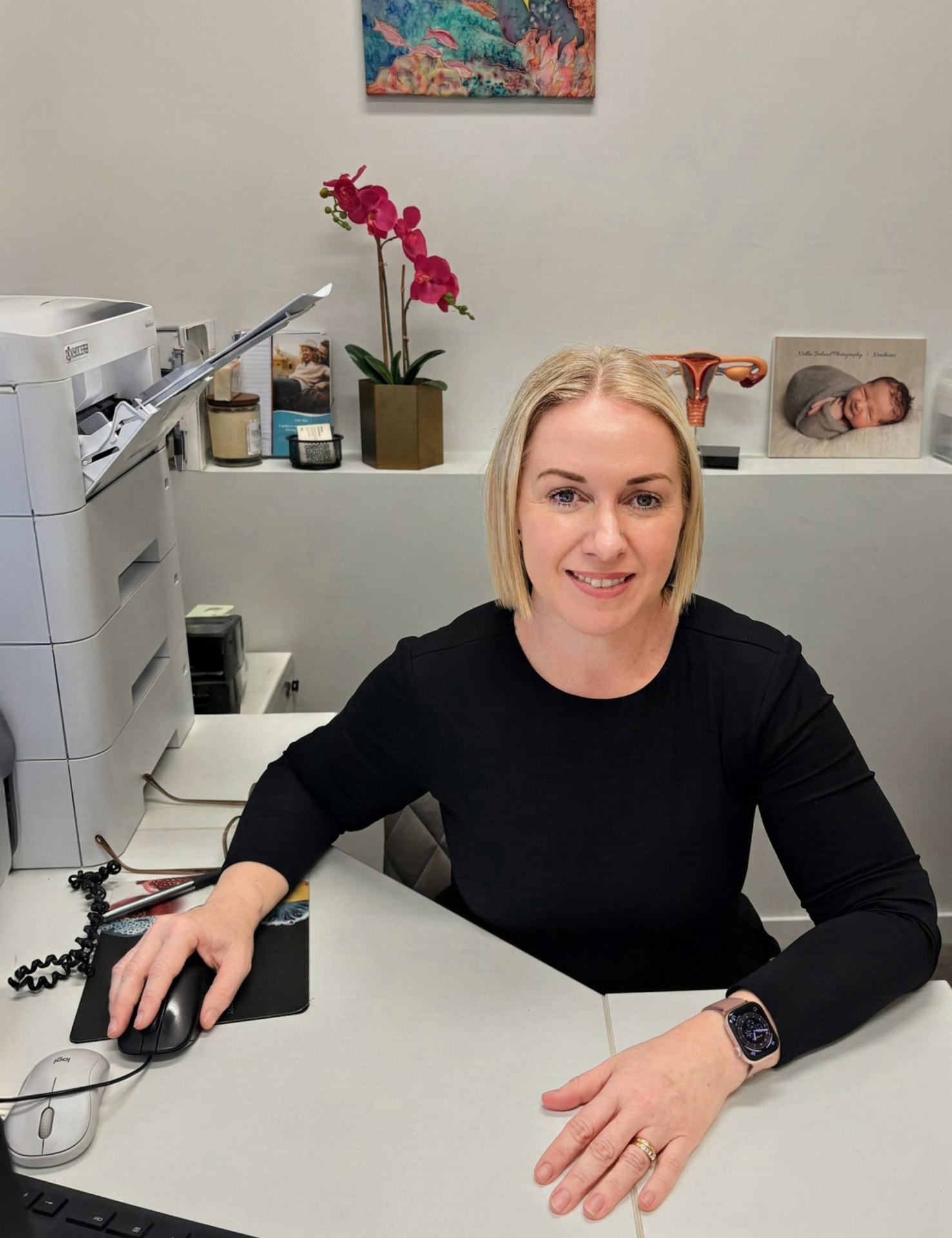 Narelle Ashworth, Endorsed Midwife, smiling at her desk in the clinic - The Midwife's Nest, Cairns